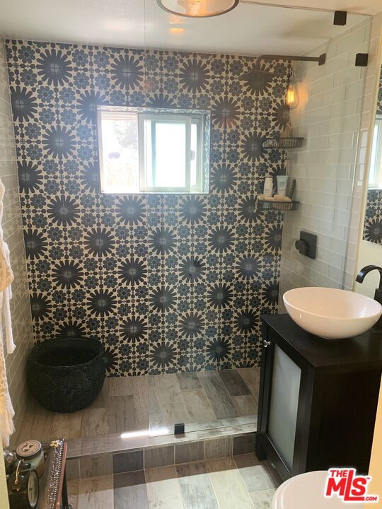 bathroom with vanity and tiled shower