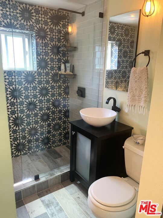 bathroom with vanity, toilet, and tiled shower