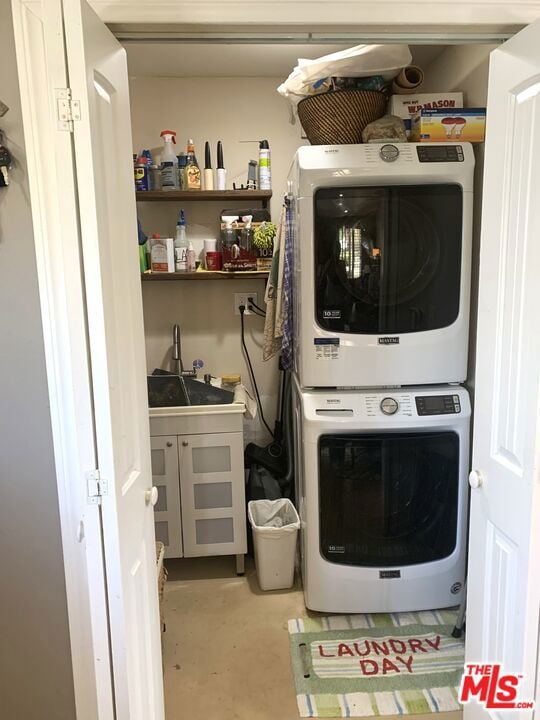 clothes washing area with stacked washer / drying machine and sink