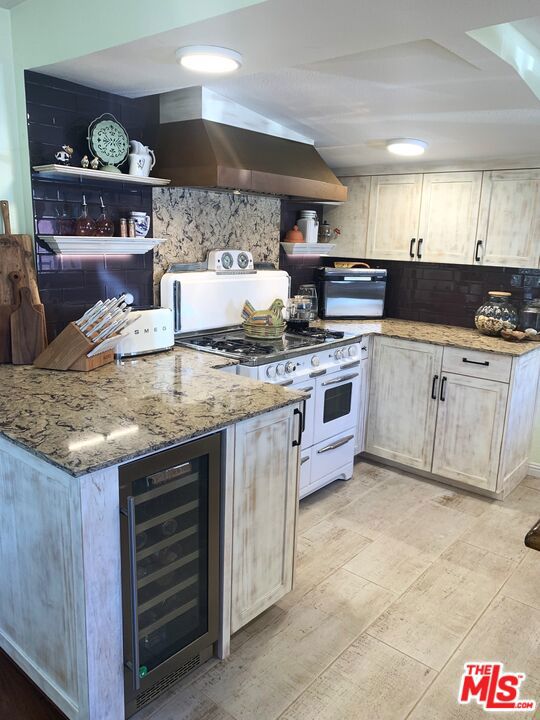 kitchen with island range hood, backsplash, beverage cooler, double oven range, and light stone countertops