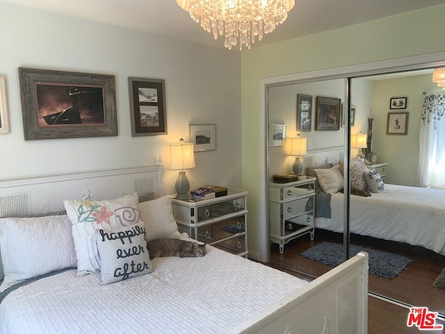 bedroom featuring a notable chandelier, dark wood-type flooring, and a closet