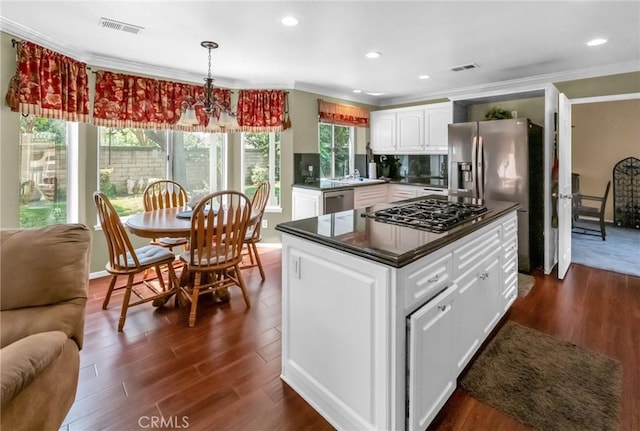 kitchen with appliances with stainless steel finishes, dark wood-type flooring, crown molding, a notable chandelier, and white cabinetry