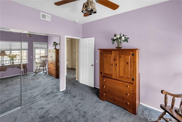 bedroom with dark colored carpet, ceiling fan, and a closet