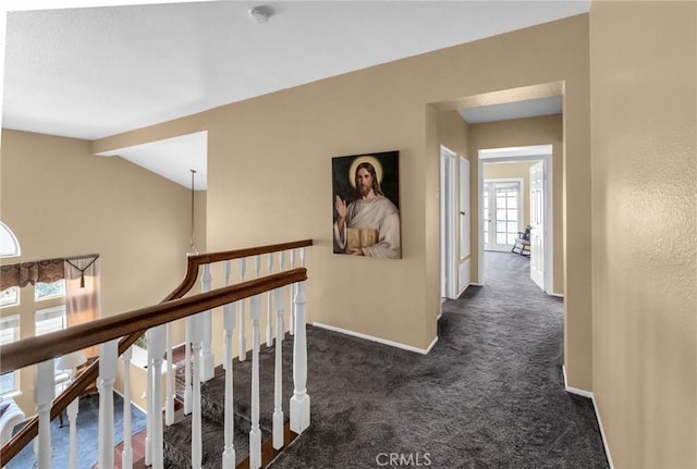 hallway featuring dark carpet and lofted ceiling