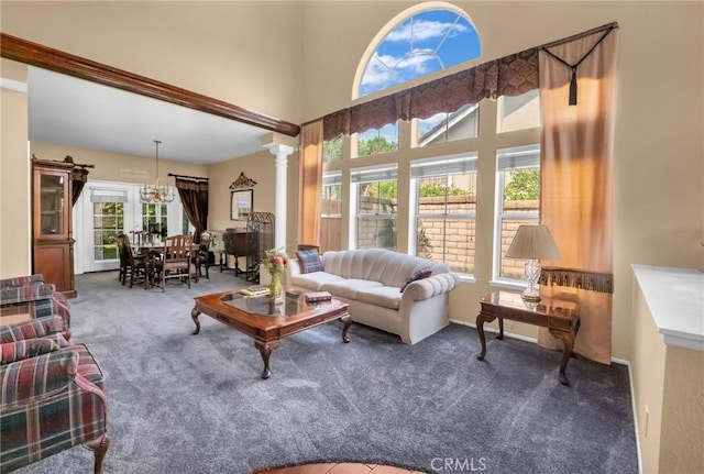 living room with ornate columns, an inviting chandelier, and dark colored carpet