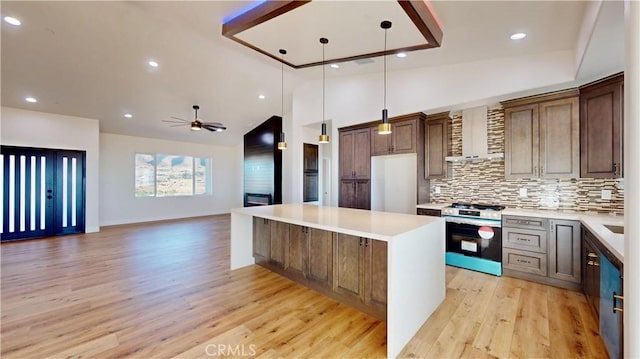 kitchen with ceiling fan, stainless steel range oven, hanging light fixtures, and light hardwood / wood-style flooring