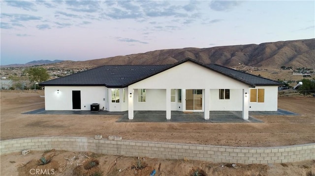 back house at dusk featuring a patio area and a mountain view