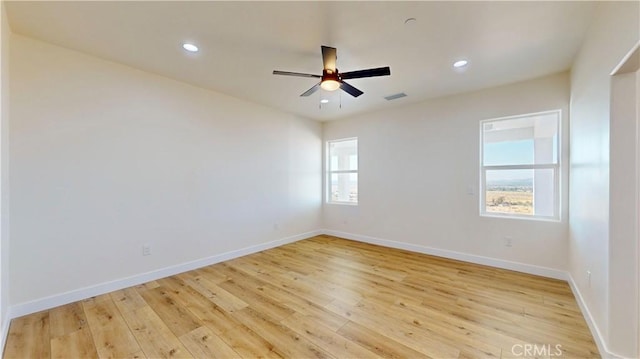 empty room with ceiling fan, plenty of natural light, and light hardwood / wood-style flooring