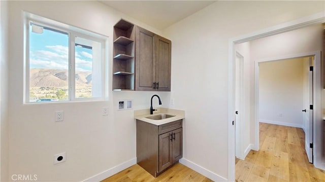 clothes washing area with sink, cabinets, hookup for an electric dryer, light hardwood / wood-style flooring, and a mountain view