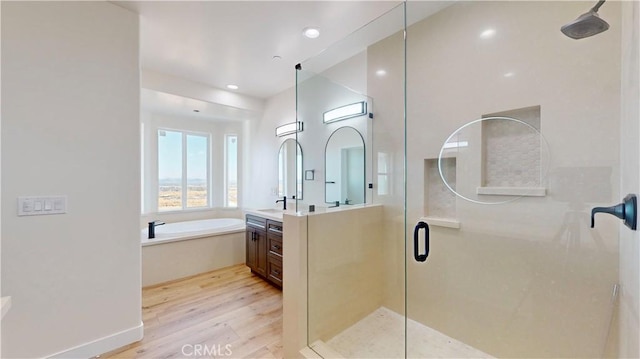 bathroom with plus walk in shower, hardwood / wood-style floors, and vanity