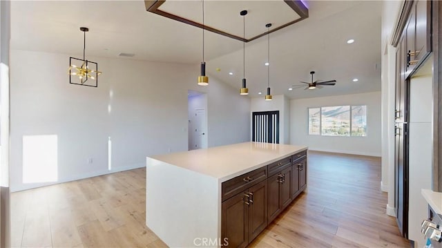 kitchen featuring ceiling fan with notable chandelier, light hardwood / wood-style flooring, hanging light fixtures, and lofted ceiling