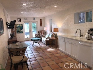 kitchen with white cabinetry, dishwasher, a textured ceiling, french doors, and sink