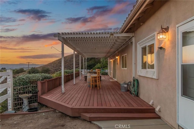 deck at dusk with a mountain view and a pergola