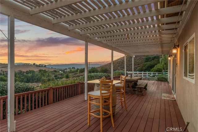 deck at dusk with a mountain view and a pergola