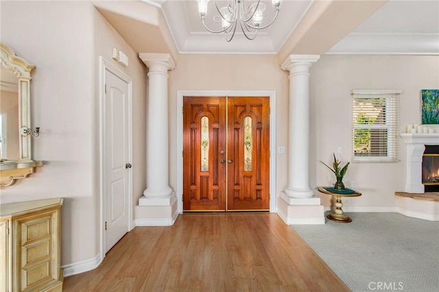 entrance foyer featuring a tray ceiling, crown molding, light hardwood / wood-style flooring, and an inviting chandelier