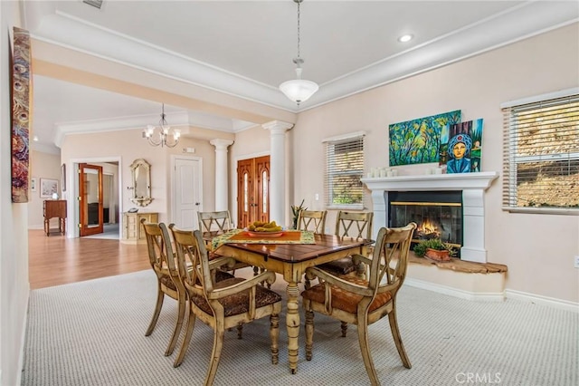 dining room featuring decorative columns, a notable chandelier, crown molding, and light hardwood / wood-style floors