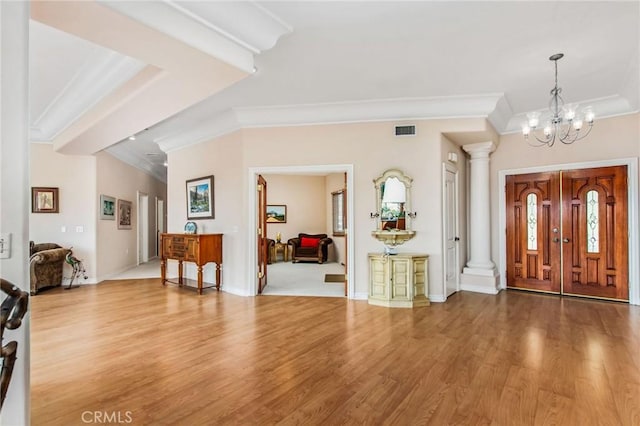 entrance foyer featuring a notable chandelier, light wood-type flooring, and crown molding