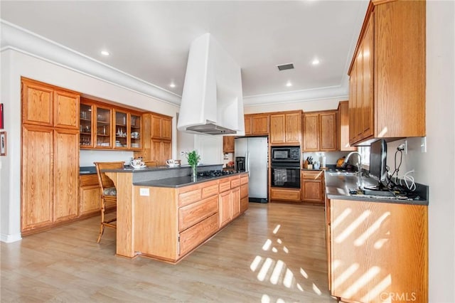 kitchen featuring premium range hood, a breakfast bar, black appliances, and light wood-type flooring