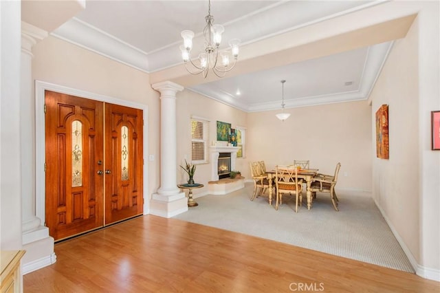 interior space featuring decorative columns, wood-type flooring, crown molding, and an inviting chandelier