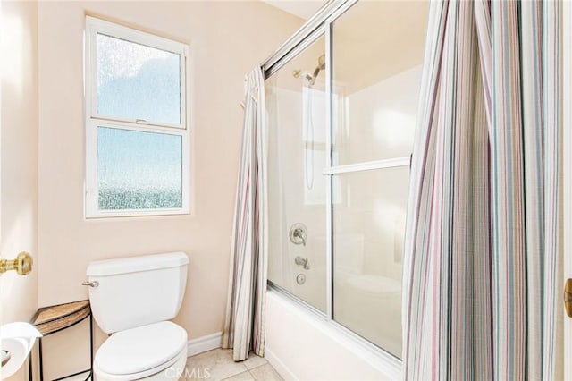 bathroom featuring tile patterned flooring, toilet, plenty of natural light, and enclosed tub / shower combo