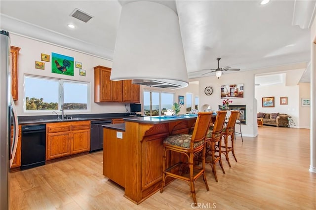 kitchen with plenty of natural light, black dishwasher, a wall mounted AC, and light hardwood / wood-style flooring