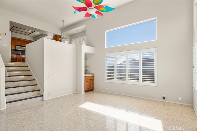 unfurnished living room featuring a towering ceiling and light tile patterned floors