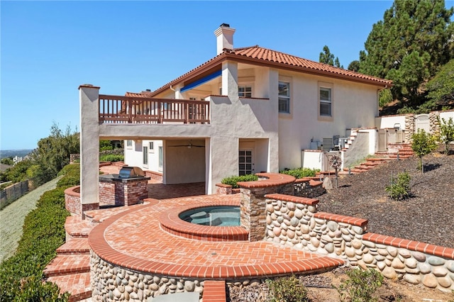 rear view of property featuring an in ground hot tub and an outdoor kitchen