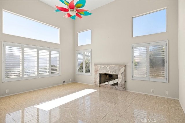 unfurnished living room featuring a high ceiling, a healthy amount of sunlight, and a premium fireplace