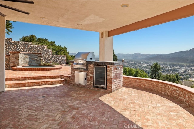 view of patio / terrace featuring a mountain view, area for grilling, and exterior kitchen