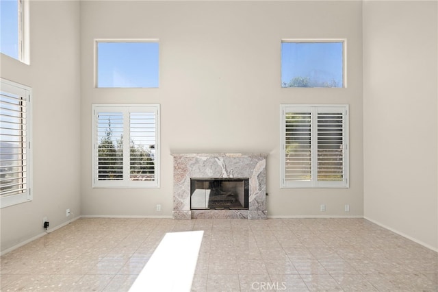 unfurnished living room featuring a high end fireplace and a high ceiling