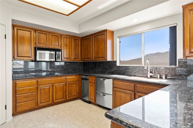 kitchen with backsplash, stainless steel appliances, dark stone counters, and sink