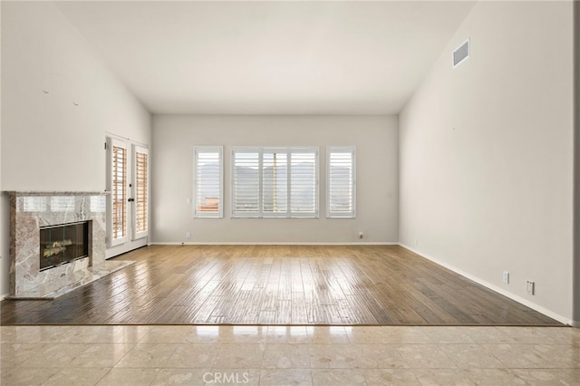 unfurnished living room with light hardwood / wood-style flooring and a high end fireplace