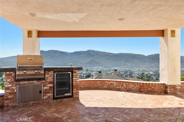 view of patio featuring area for grilling, a mountain view, wine cooler, and a grill