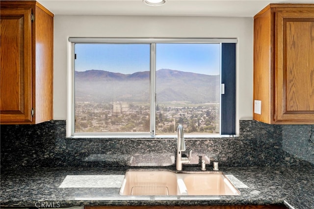 kitchen with backsplash, a mountain view, sink, and dark stone counters