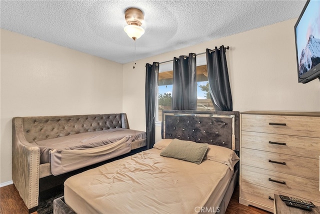 bedroom with ceiling fan, a textured ceiling, and dark hardwood / wood-style flooring