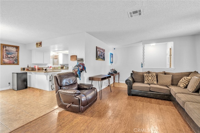 living room featuring a textured ceiling and light hardwood / wood-style floors