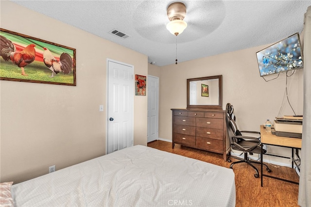 bedroom with a textured ceiling, dark wood-type flooring, and ceiling fan