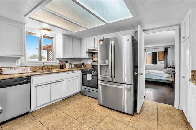 kitchen featuring appliances with stainless steel finishes, light tile patterned flooring, sink, and white cabinets