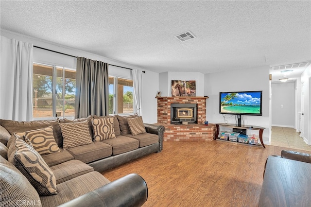 living room featuring light hardwood / wood-style flooring, a textured ceiling, and a fireplace