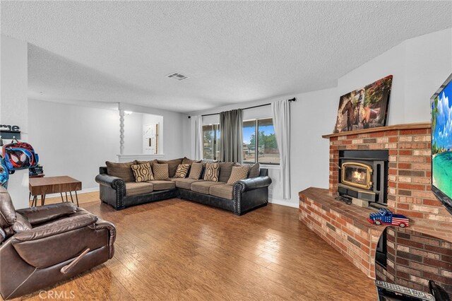 living room with a textured ceiling, a fireplace, hardwood / wood-style floors, and a wood stove