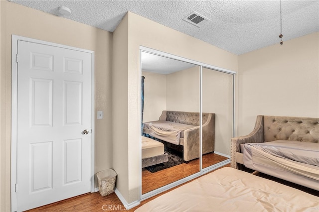 bedroom featuring a textured ceiling, hardwood / wood-style floors, and a closet