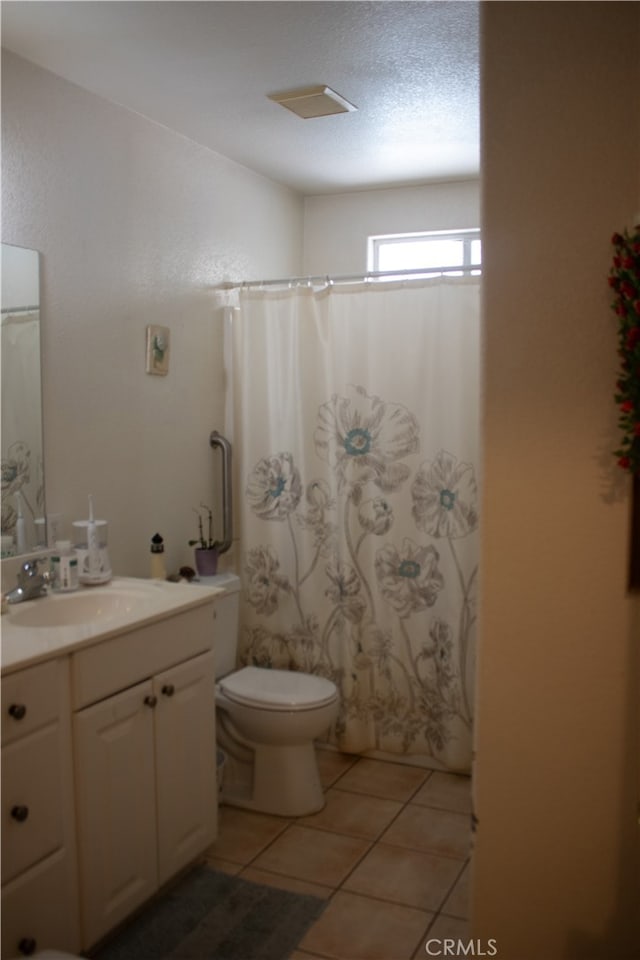 bathroom with vanity, toilet, a textured ceiling, walk in shower, and tile patterned flooring