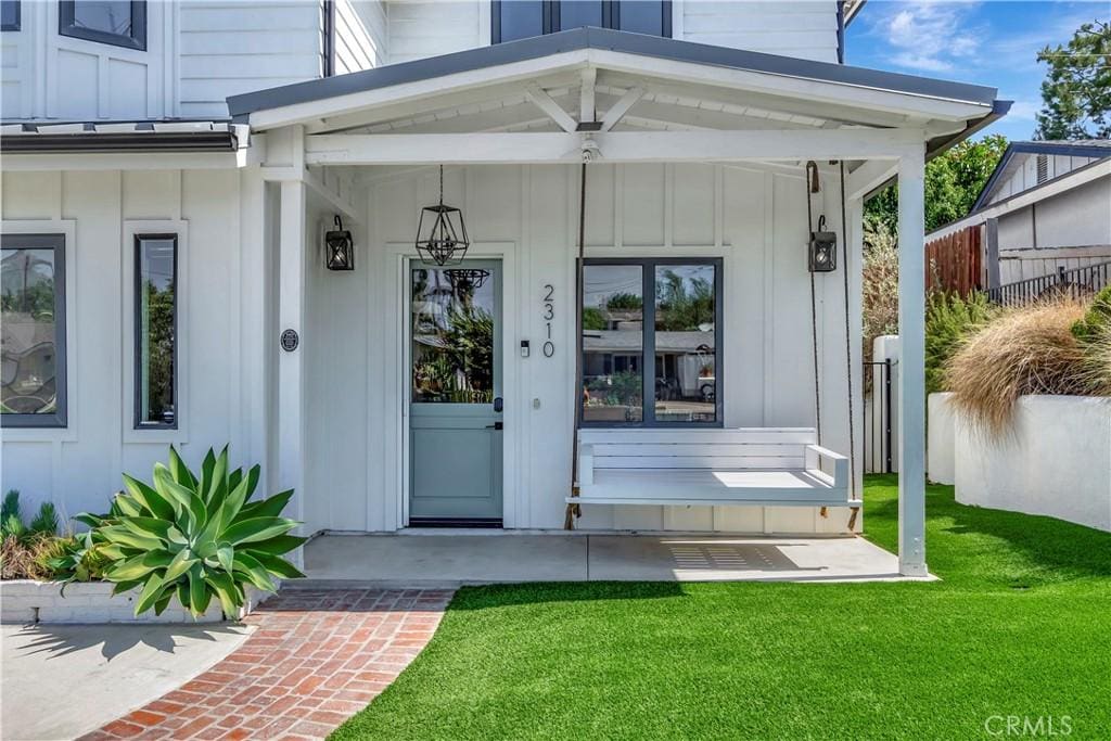 entrance to property with a porch and a lawn