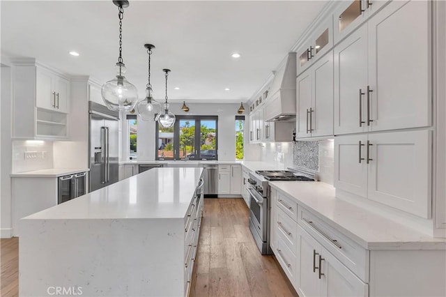 kitchen with a kitchen island, custom range hood, white cabinetry, and premium appliances