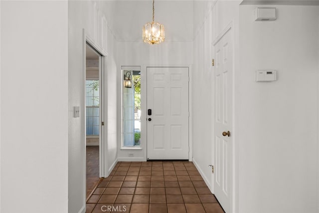 foyer entrance with dark tile patterned floors and a chandelier