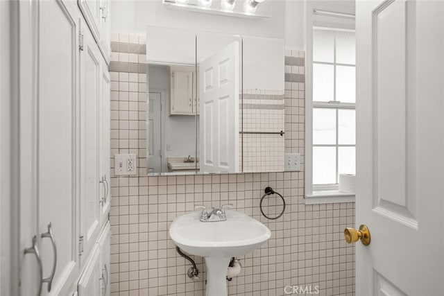 bathroom featuring sink and tile walls