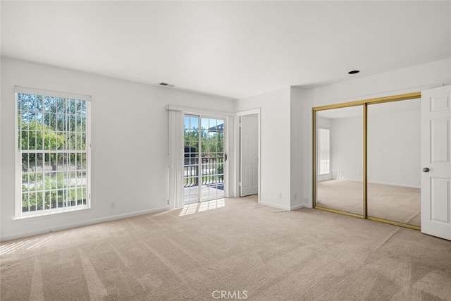 unfurnished bedroom featuring light colored carpet, access to outside, and a closet