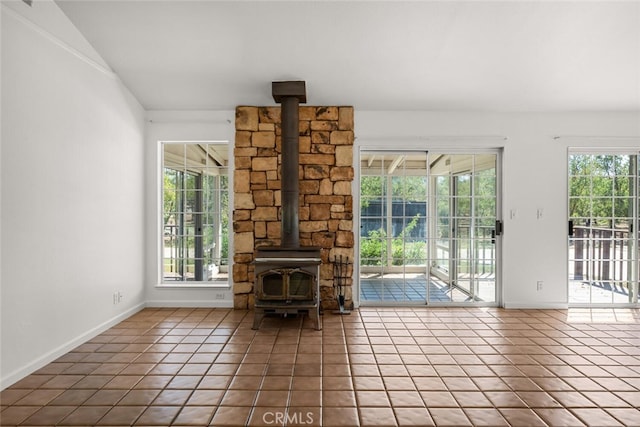 unfurnished living room featuring tile patterned floors, a wood stove, and lofted ceiling