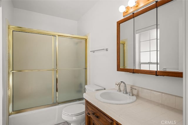 full bathroom featuring vanity, toilet, and shower / bath combination with glass door