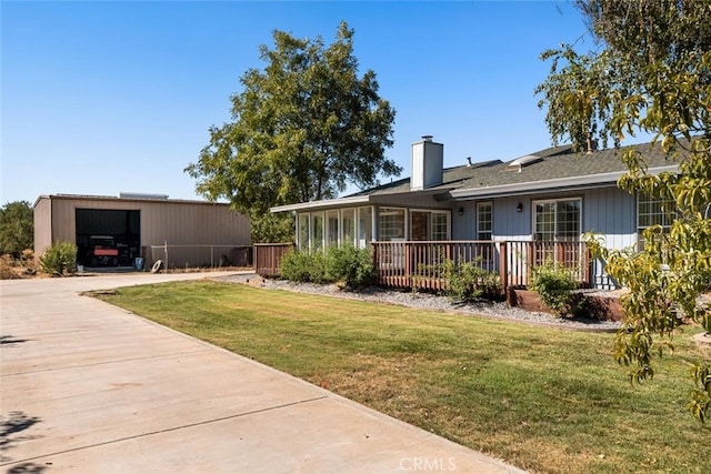 view of front of house featuring a garage, a front lawn, and an outdoor structure